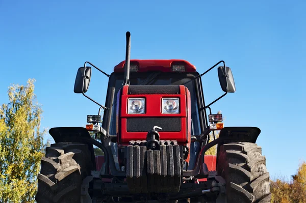 Modern red tractor on a blue sky background.