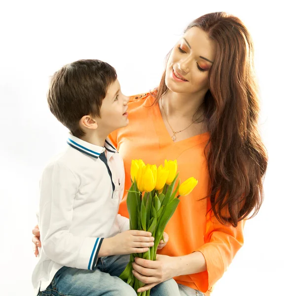 Son hugging his mother and gives her flowers