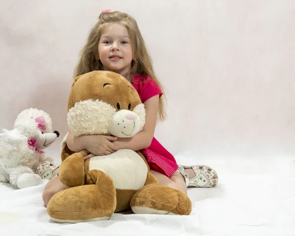 The lovely girl embraces a big soft toy hare