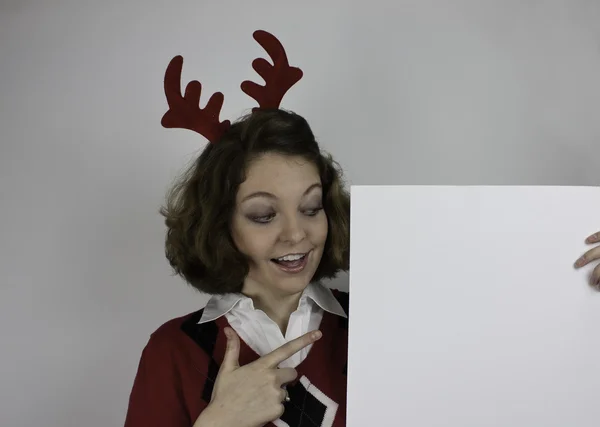 年轻漂亮的女人戴鹿角及持空白符号 - 图库照片