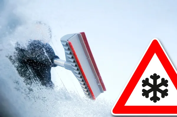 Winter driving - woman scraping ice from a windshield