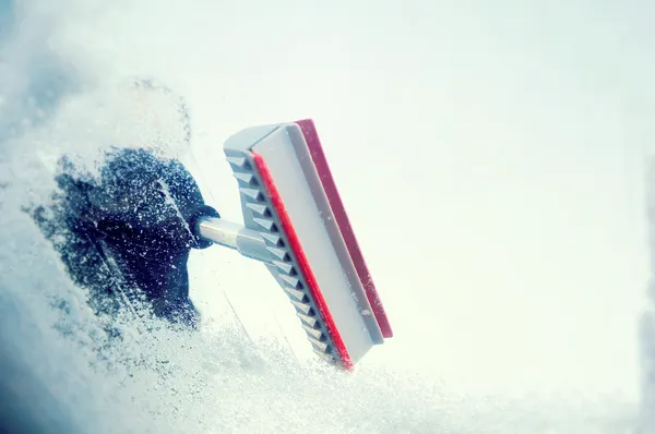 Winter driving - woman scraping ice from a windshield