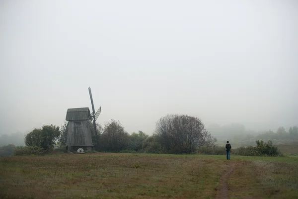 Mill in fog. Lonely person in the field