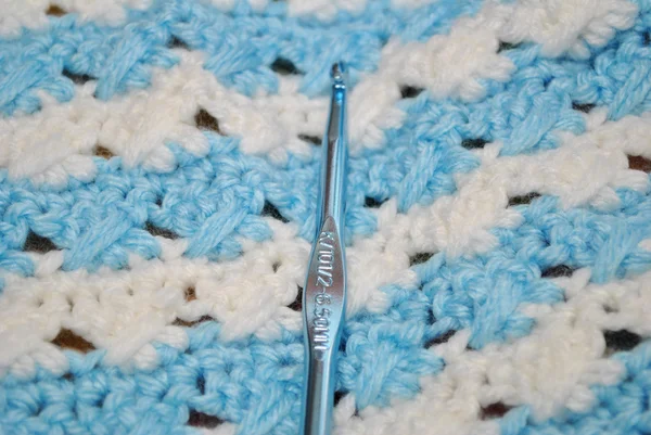A Crochet Hook on a Blue and White Blanket