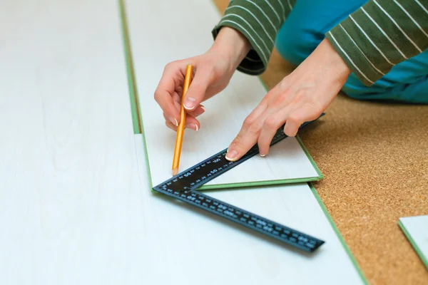 Woman drawing cut line on laminate board