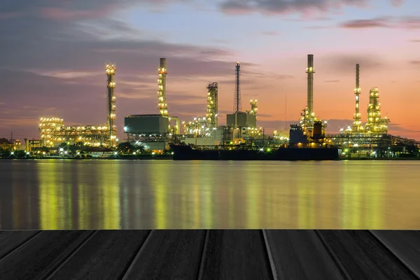 Wood planks floor with Oil refinery plant at twilight background