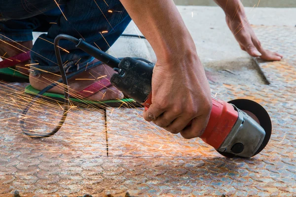 Worker cutting metal with grinder. Sparks while grinding iron