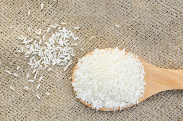 Raw rice on wooden ladle