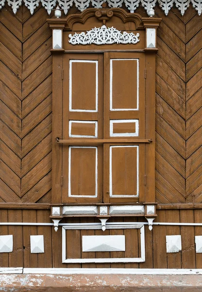 Old wooden window with carved wooden ornaments. Closed window.