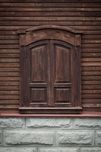 Old wooden window with carved wooden ornaments. Closed window.