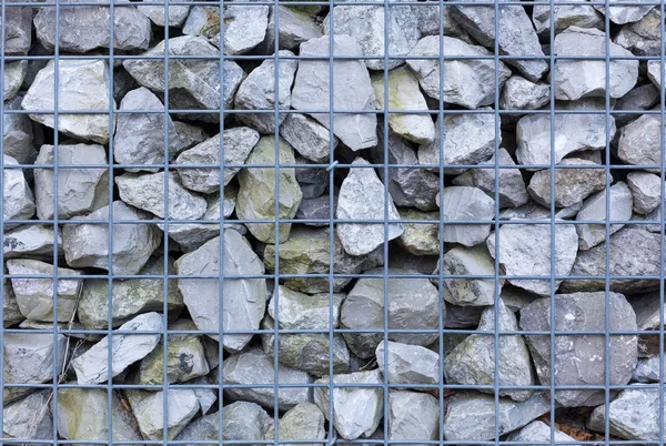 Stone wall behind iron net