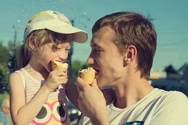 Father and daughter eating ice cream while walking