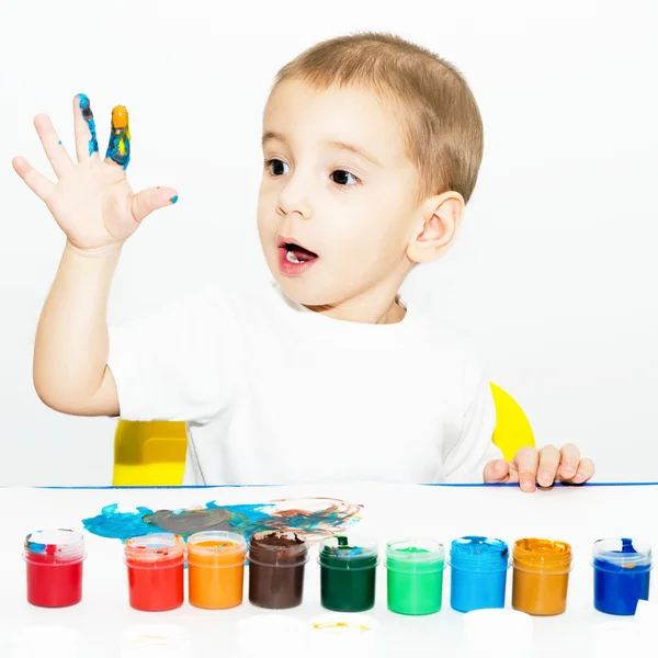 Little boy draws fingers with paint