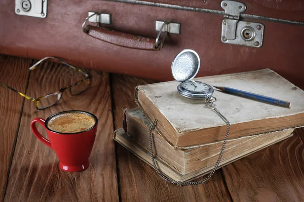 Cup of coffee, vintage suitcase, watches, glasses and old books