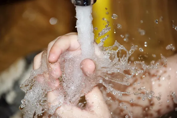 The child washes hands under the crane