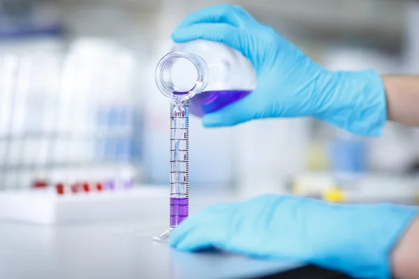 Decanting a violet liquid into a graduated cylinder