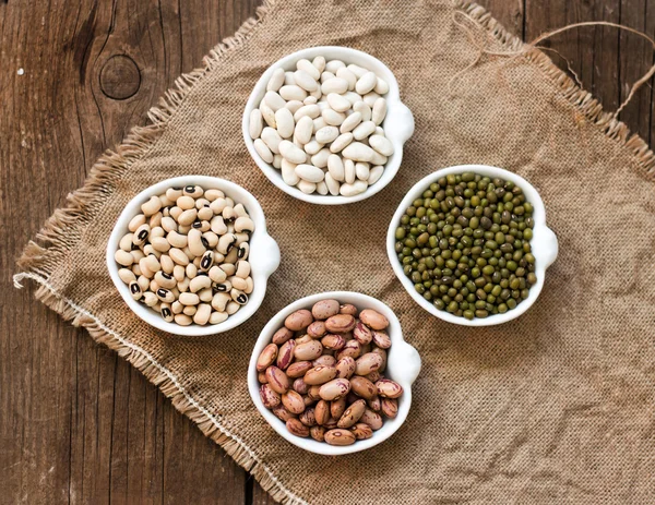 Assortment of legumes in bowls on wooden table