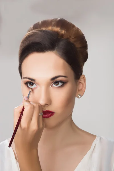 Beautiful girl applying make-up by make-up artist