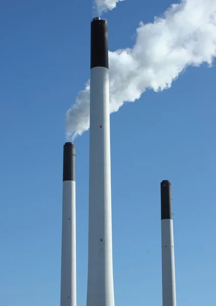 Factory chimneys at energy plant with blue sky and lake