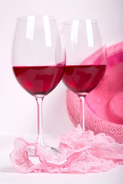 Two glasses of red wine on a white background near pink panties