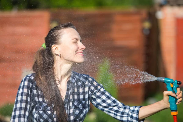 Woman watering lawn with garden hose