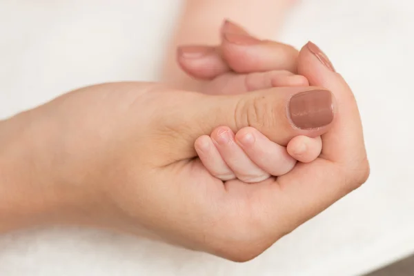 Baby's hand gripping adult finger