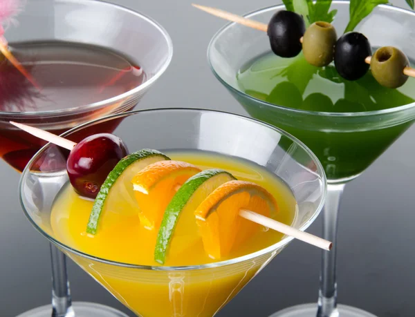 Orange, cherry and green vegetables cocktails on a gray backgrou