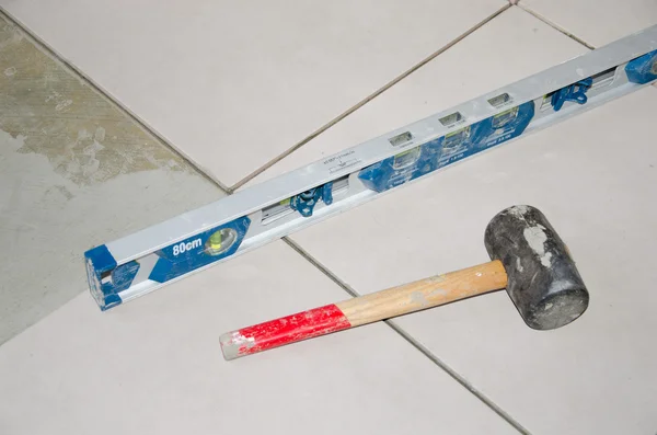 Bubble level and rubber mallet on a floor tiling