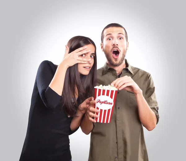 Young couple watching a movie and eating popcorn