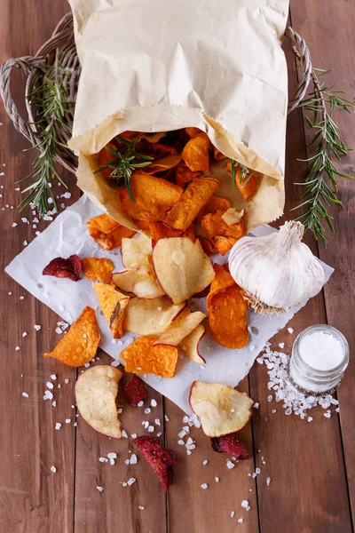 Healthy vegetable chips on paper with sea salt, rosemary and garlic