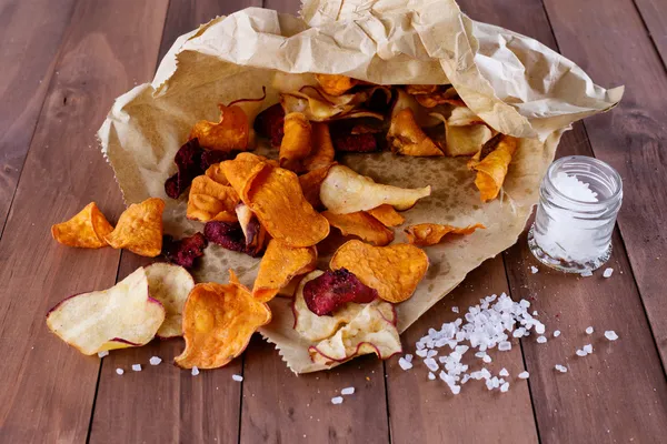 Healthy vegetable chips on paper with sea salt