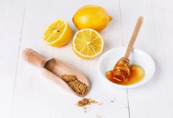 Organic lemons with honey and brown sugar over white background
