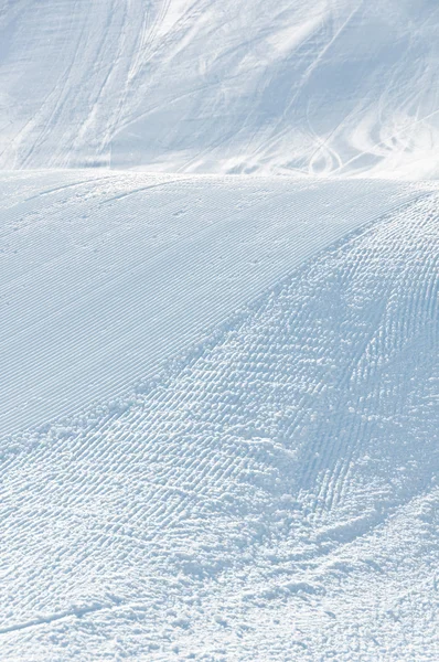 Alpine ski piste with ski and snowboard tracks