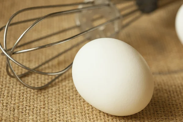 An Egg and whisk isolated on table mat