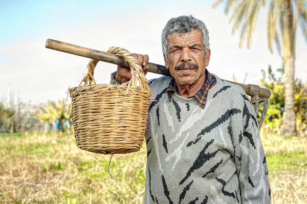Senior farmer holding a fork and a straw basket