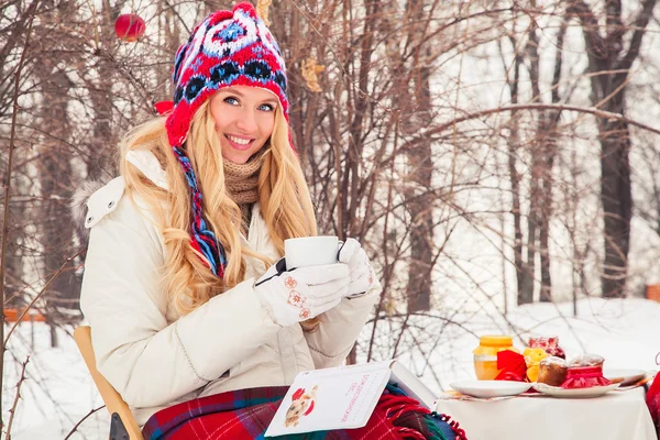 Portrait of a beautiful woman is drinking tea or coffee in the fresh air in the winter.