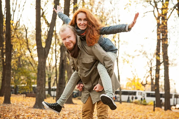 Love story. Autumn Park. Man and woman in a city park tells the story of his love. Happy people having fun. Woman on top of a man on his back.