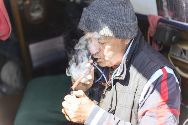Old man smokes cigar