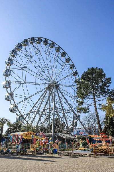 Ferris wheel with close cabins on the blue sky in the park