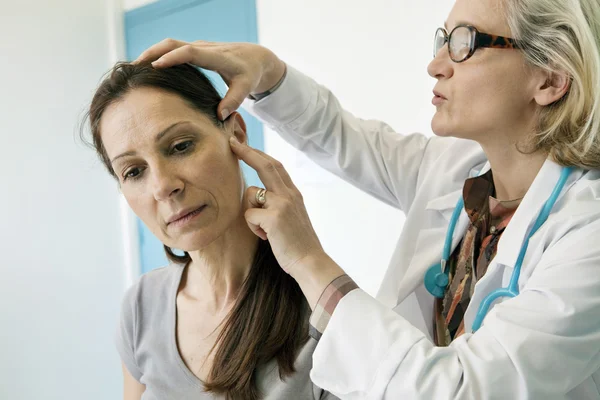 Doctor examines woman's ear