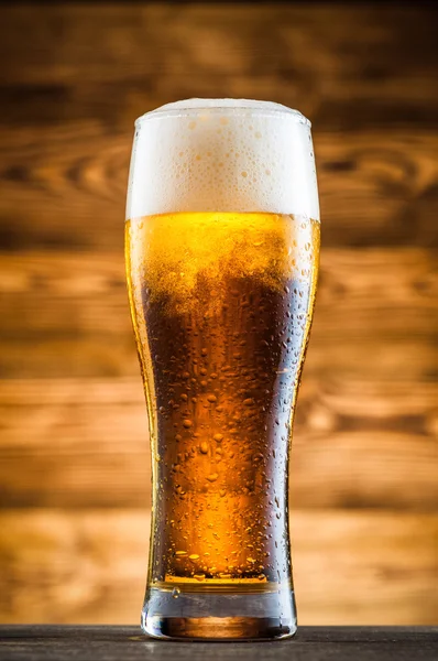 Glass of cold beer on wooden table