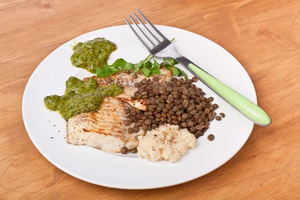 Healthy baked tilapia fish garnished with lentil, couscous and p