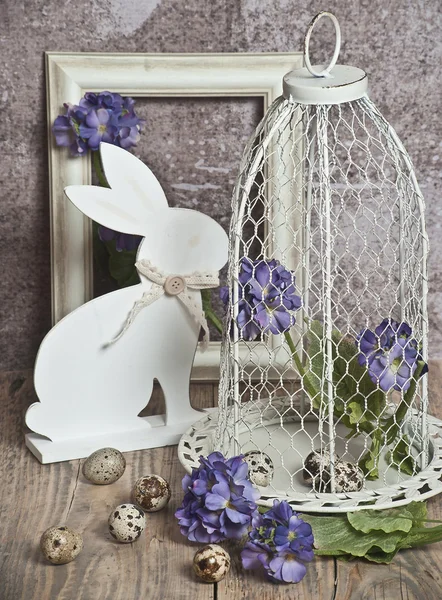 Easter eggs in a cage, spring blue  flowers, quail eggs, white bunnies  , white frame, white frame, wooden floor  nature