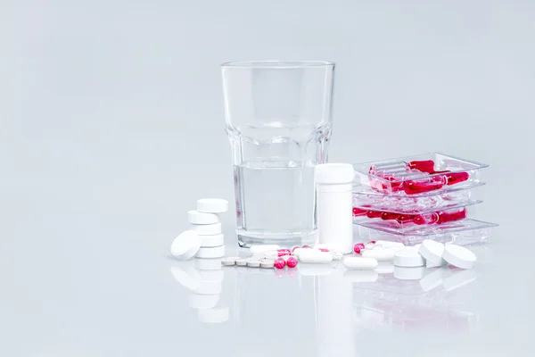 Medicines on white with a glass of water
