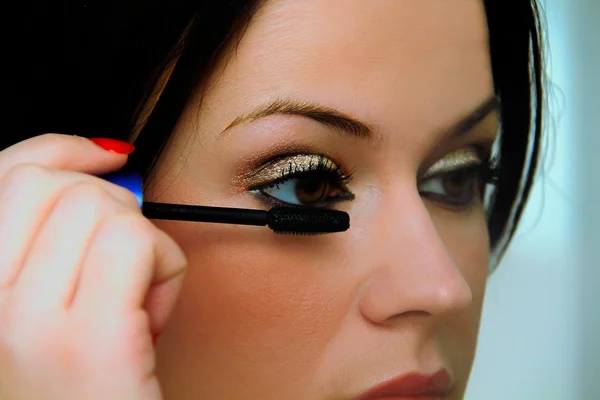 Beautiful woman making up eyelashes herself