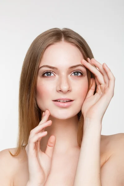 Young beautiful brunette woman with natural makeup on grey background