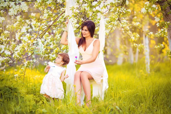 Happy woman and child in the blooming spring garden.Mothers day