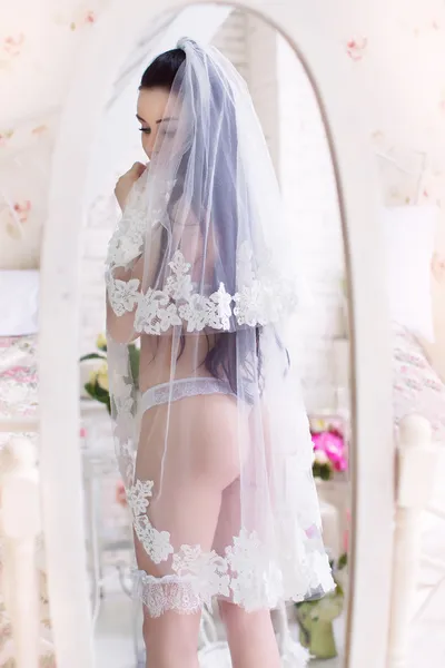 Beautiful young bride in the veil, and with garter stands in fro