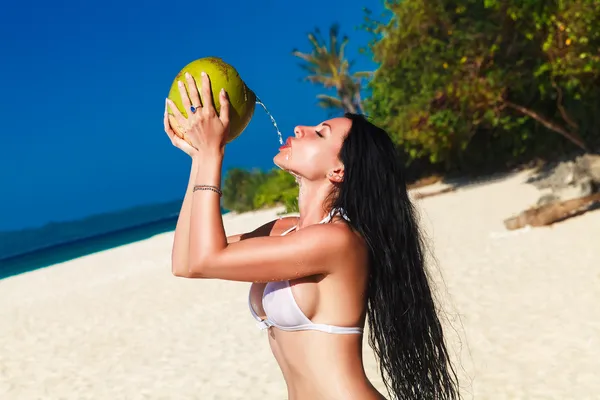 Young beautiful woman with long black hair in white bikini, drin