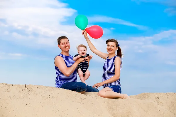 Happy family, mom, dad and little son in striped vests having fu